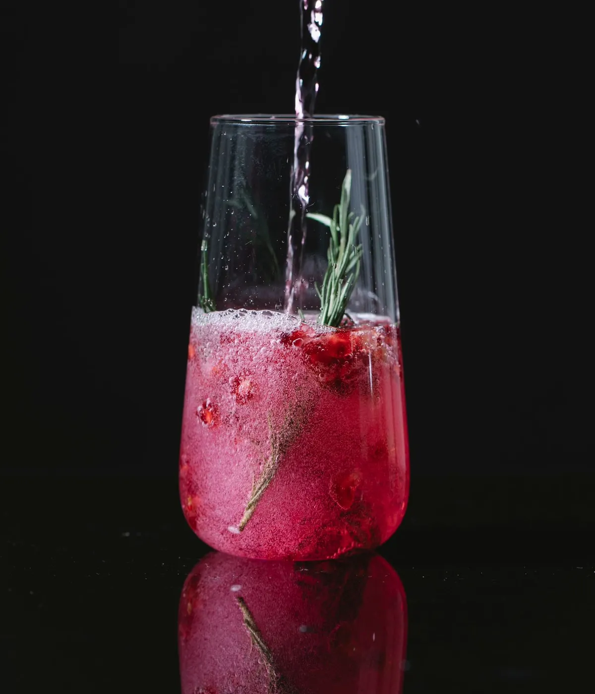Cóctel con frutos rojos y romero sobre un fondo negro
